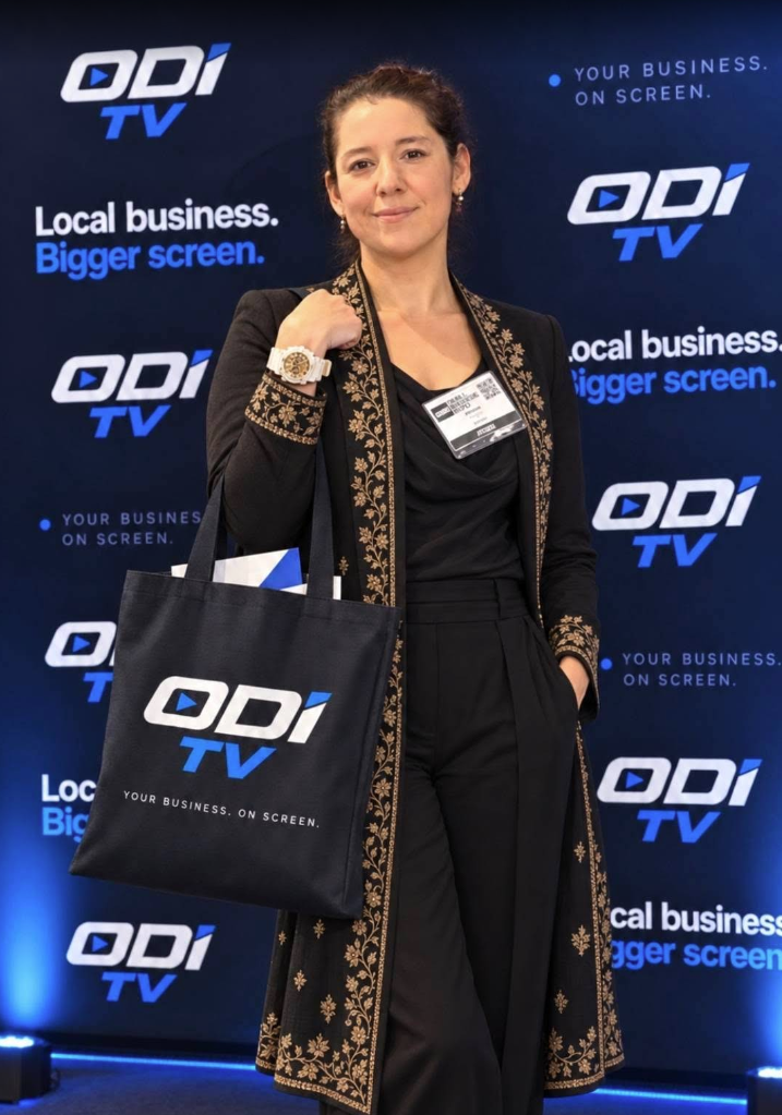 Woman holding an ODI TV tote bag in front of the ODI TV event backdrop